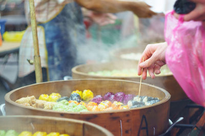 Cropped image of hand picking food from wooden container