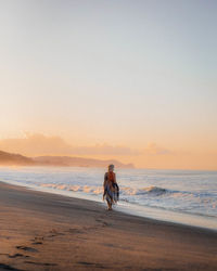 Man on beach against sky during sunset