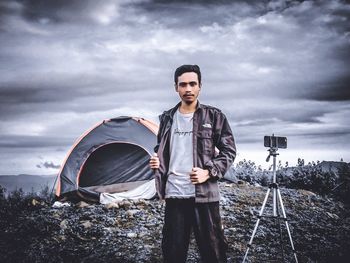 Portrait of young man photographing against sky