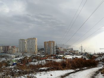 Snow covered buildings in city against sky