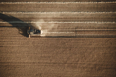 Combine harvester working at sunset from aerial view.