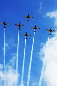 Low angle view of airplanes with trails in flight