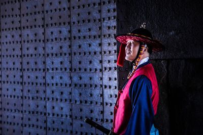 Portrait of young woman looking away against wall