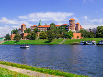 Buildings by river against sky