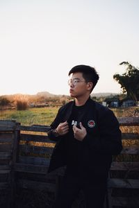 Young man looking away against sky