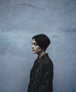 Young woman standing against colored wall