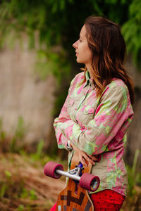 Thoughtful woman holding skate while standing outdoors