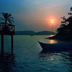 Silhouette of boat in sea at sunset