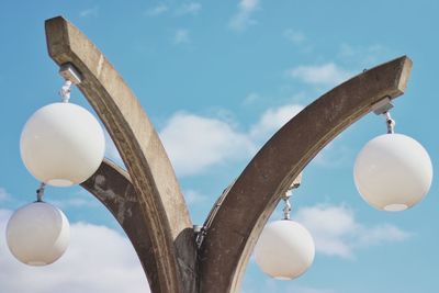 Low angle view of a concrete lamp with four lights against a blue sky with white clouds