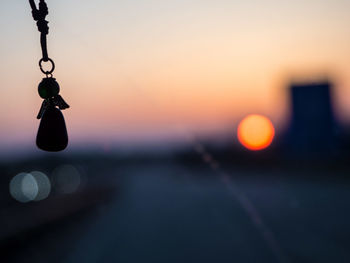 Close-up of hanging lights against sky during sunset