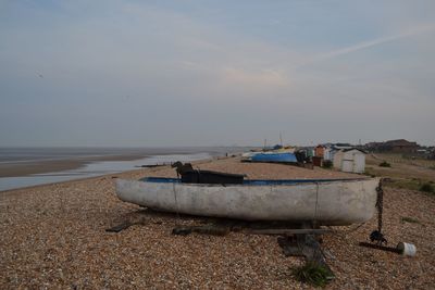 Boat moored on beach against sky