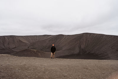 Rear view of man walking on mountain against sky