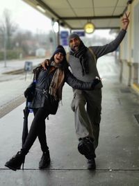 Full length portrait of happy couple walking on railroad station