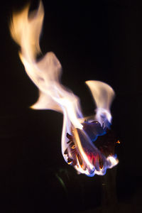 Close-up of burning candle against black background