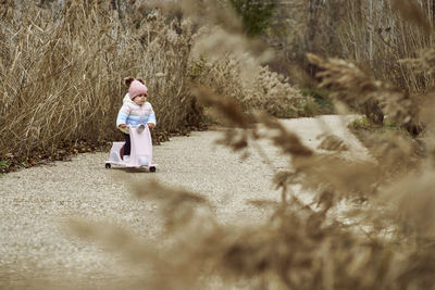 A 1 year old baby girl is with a pink motorcycle outside