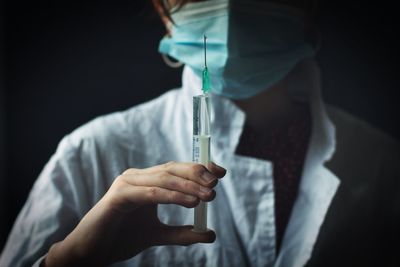 Midsection of doctor holding syringe