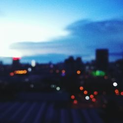 Defocused image of illuminated city against sky at night