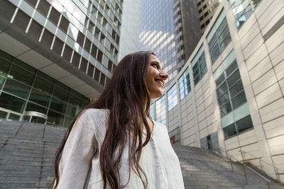 Portrait of young woman standing against building