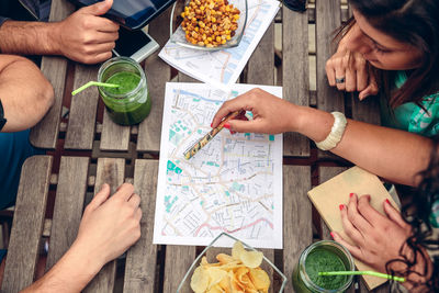 High angle view of friends discussing on map while sitting in restaurant