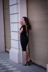 Full length of woman standing against brick wall