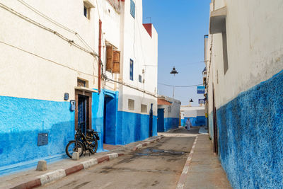 Street amidst buildings against blue sky