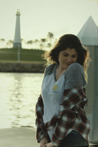 Beautiful young woman standing against sky