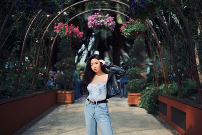 Full length portrait of woman standing by flowering plants