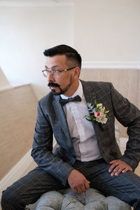 Young man looking away while sitting at home