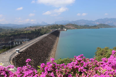 Scenic view of sea by mountain against sky