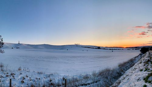 Scenic view of snow covered field against sky during sunset