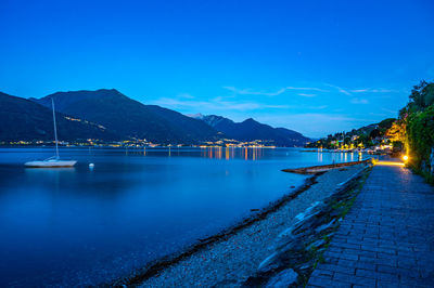 The town of pianello del lario, on lake como, and the promenade along the lake, at dusk.