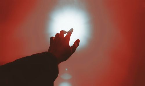 Close-up of silhouette hand against illuminated red light
