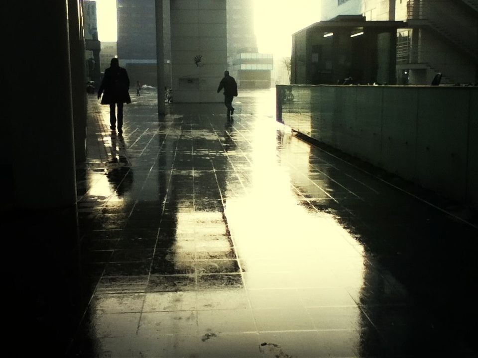 architecture, built structure, building exterior, walking, reflection, silhouette, men, city, sunlight, building, lifestyles, full length, street, water, window, wet, city life, shadow, person