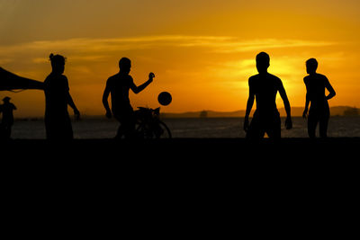 Young people playing beach soccer during sunset at ribeira beach in salvador, bahia, brazil.