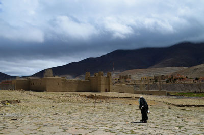 Man on street amidst buildings against sky