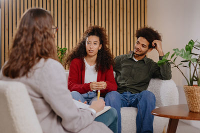 Portrait of smiling friends sitting on sofa at home