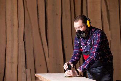 Young man using mobile phone while standing on wood