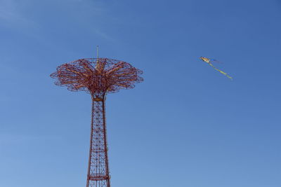 Low angle view of tower and kite against clear blue sky