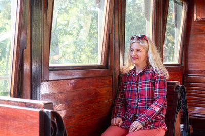 Woman dressed in a royal stewart red tartan shirt sitting in a vintage train - sarganska 8