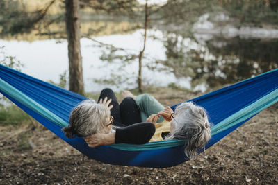 Two senior women resting in hammock at lakeshore