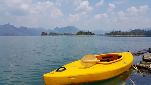 Yellow boat floating on lake against sky