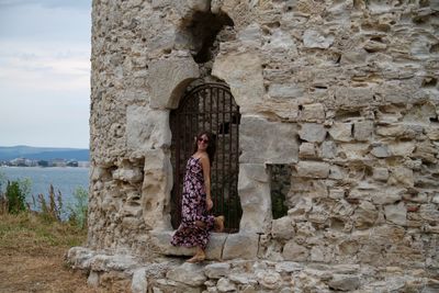 Woman standing on stone wall at beach