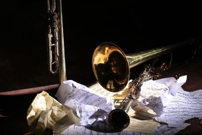 Close-up of musical instrument by crumpled paper against black background