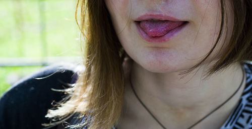 Cropped image of young woman sticking out tongue