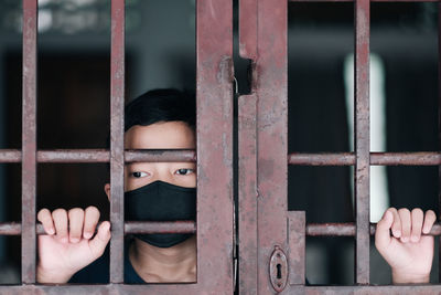 Boy wearing mask standing behind metallic door