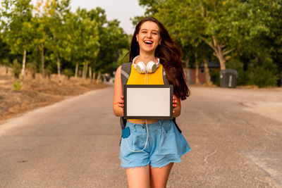 Portrait of a smiling young woman standing on road
