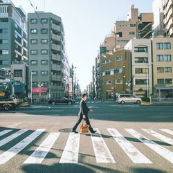 Full length of man walking on city street against buildings