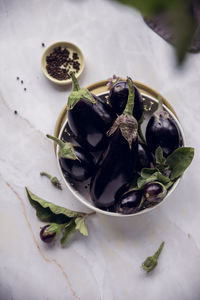 Purple eggplants of various shapes on a platter on light table