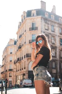 Portrait of woman standing against buildings in city