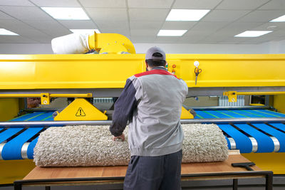 Rear view of man working on yellow umbrella